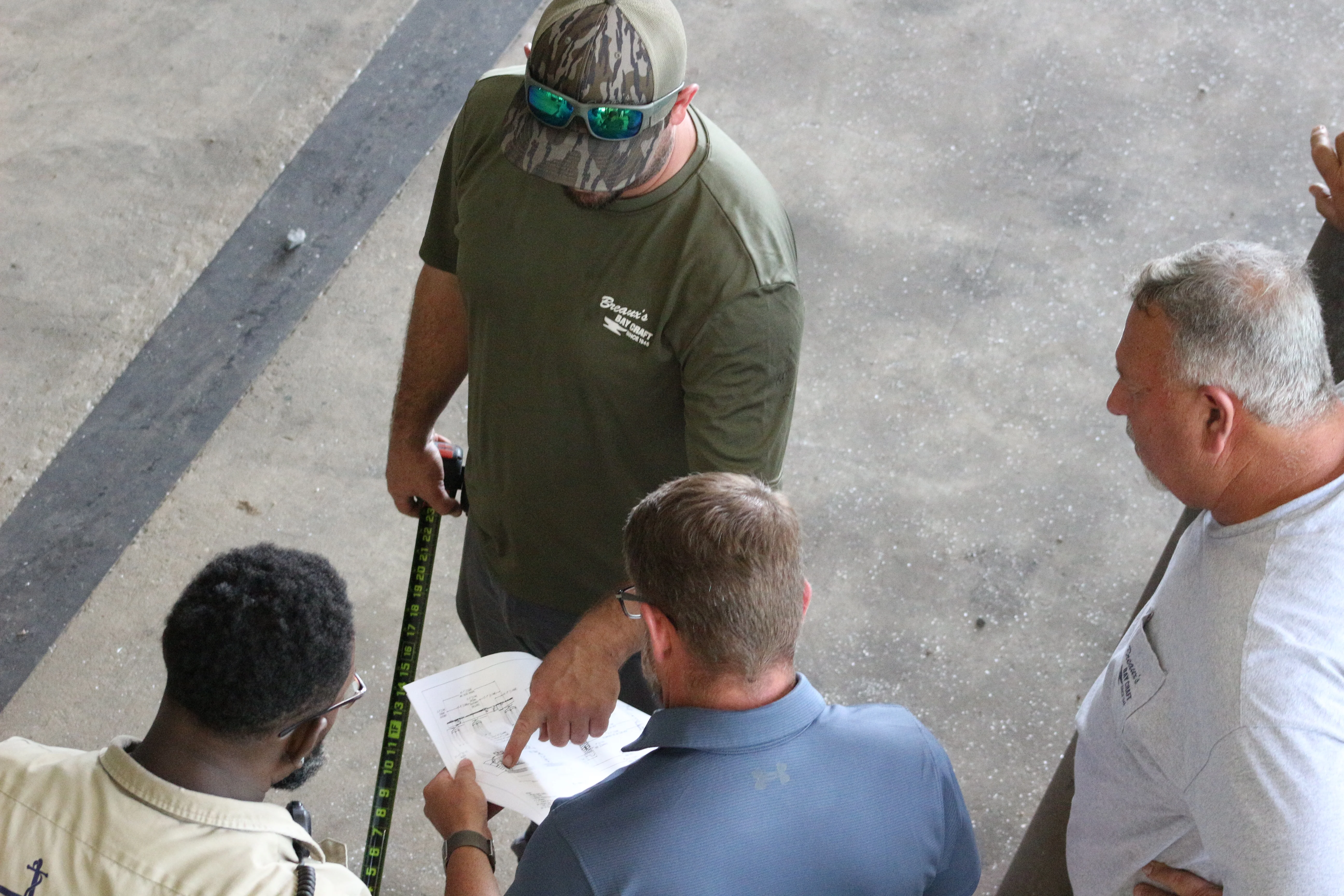 Workers reviewing aluminum boat drawings and pointing at plans — Breaux's Bay Craft news and dispatch