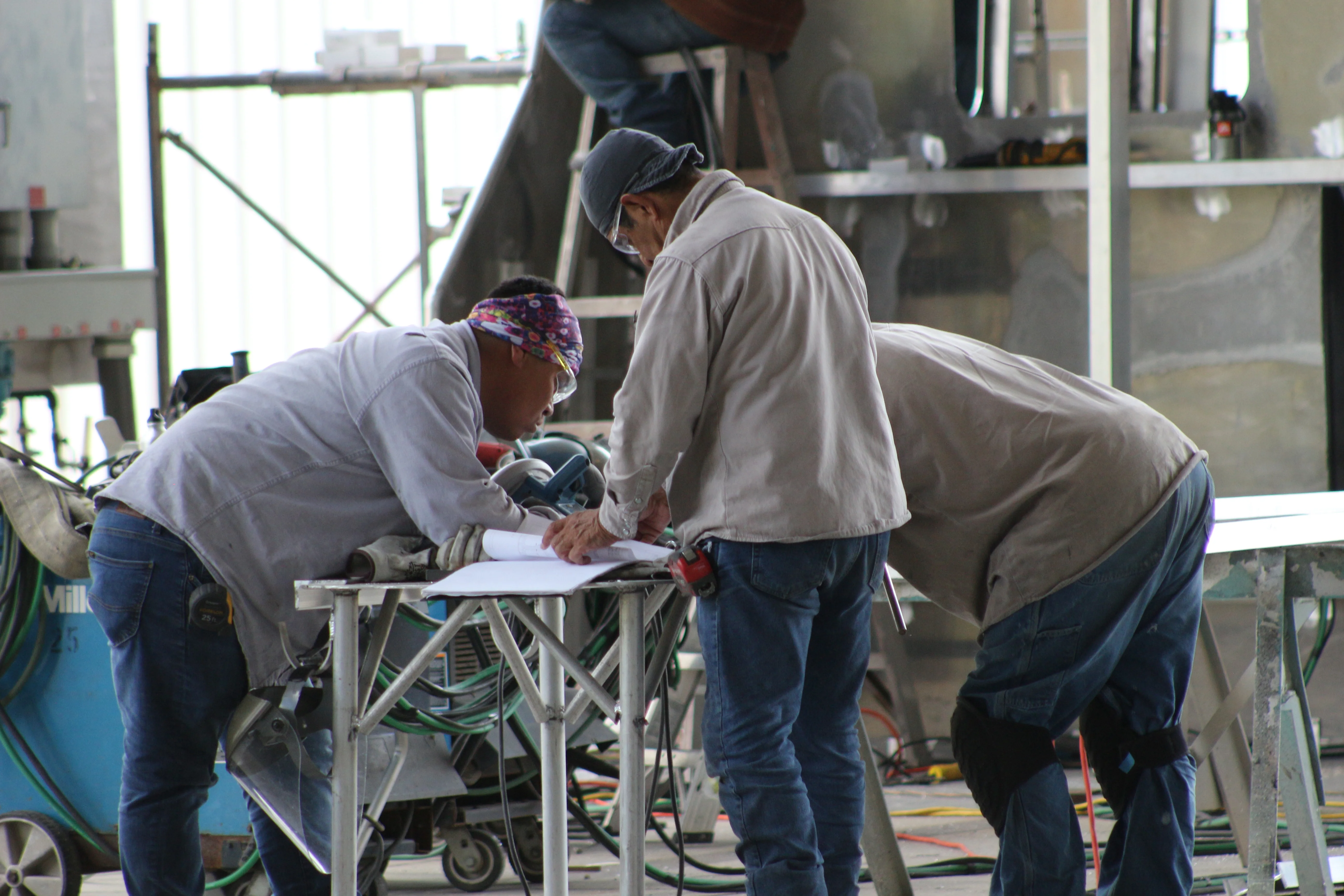 Shipyard workers reviewing fabrication plans in the workshop